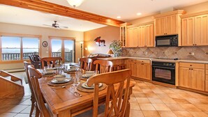 A spacious kitchen with wooden cabinets, a dining table set for six, and a view through the windows.