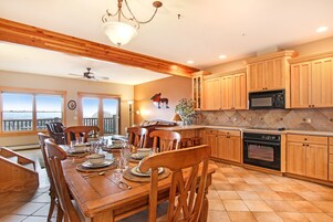 Una cocina amplia con armarios de madera, una mesa de comedor preparada para seis comensales y vistas a través de las ventanas.
