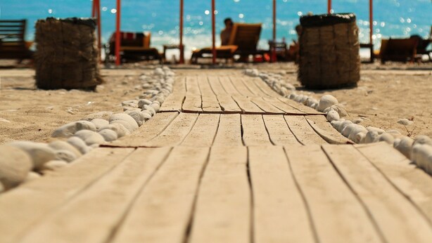 A wooden boardwalk leading to beach umbrellas and lounge chairs. - Drymades Resort (Himarë)