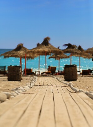 A wooden boardwalk leading to beach umbrellas and lounge chairs. - Drymades Resort (Himarë)