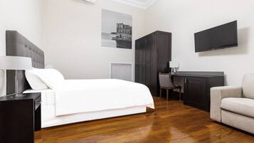 Una camera d'albergo con un letto, una scrivania, una sedia, una TV e un divano.