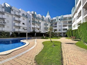A modern apartment building with a swimming pool, a small garden, and a clear blue sky. - R. Marine II 231 - Piso con piscina, Roses (Rosas / Roses)