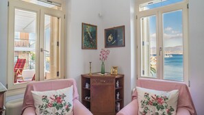 Een kamer met twee roze fauteuils, een houten kast en twee schilderijen aan de muur.