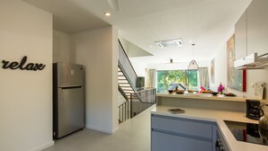 Eine moderne Küche mit integriertem Kühlschrank, ein Essbereich mit Blick aus dem Fenster und eine Treppe, die zu einer anderen Ebene führt.