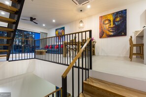 Un intérieur moderne agrémenté d’un escalier, d’une rambarde en bois et d’œuvres d’art accrochées aux murs.