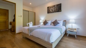 Ein Hotelzimmer mit einem großen Bett, Nachttischlampen, einem an der Wand befestigten Kunstwerk und Holzboden.