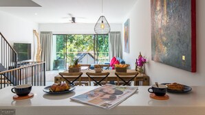 Ein moderner Essbereich mit Blick ins Freie, einem Deckenventilator und einem großen abstrakten Gemälde an der Wand.