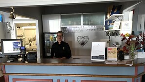 Un comptoir d’accueil équipé d’un écran d’ordinateur, d’une caisse enregistreuse et d’un téléphone portable.