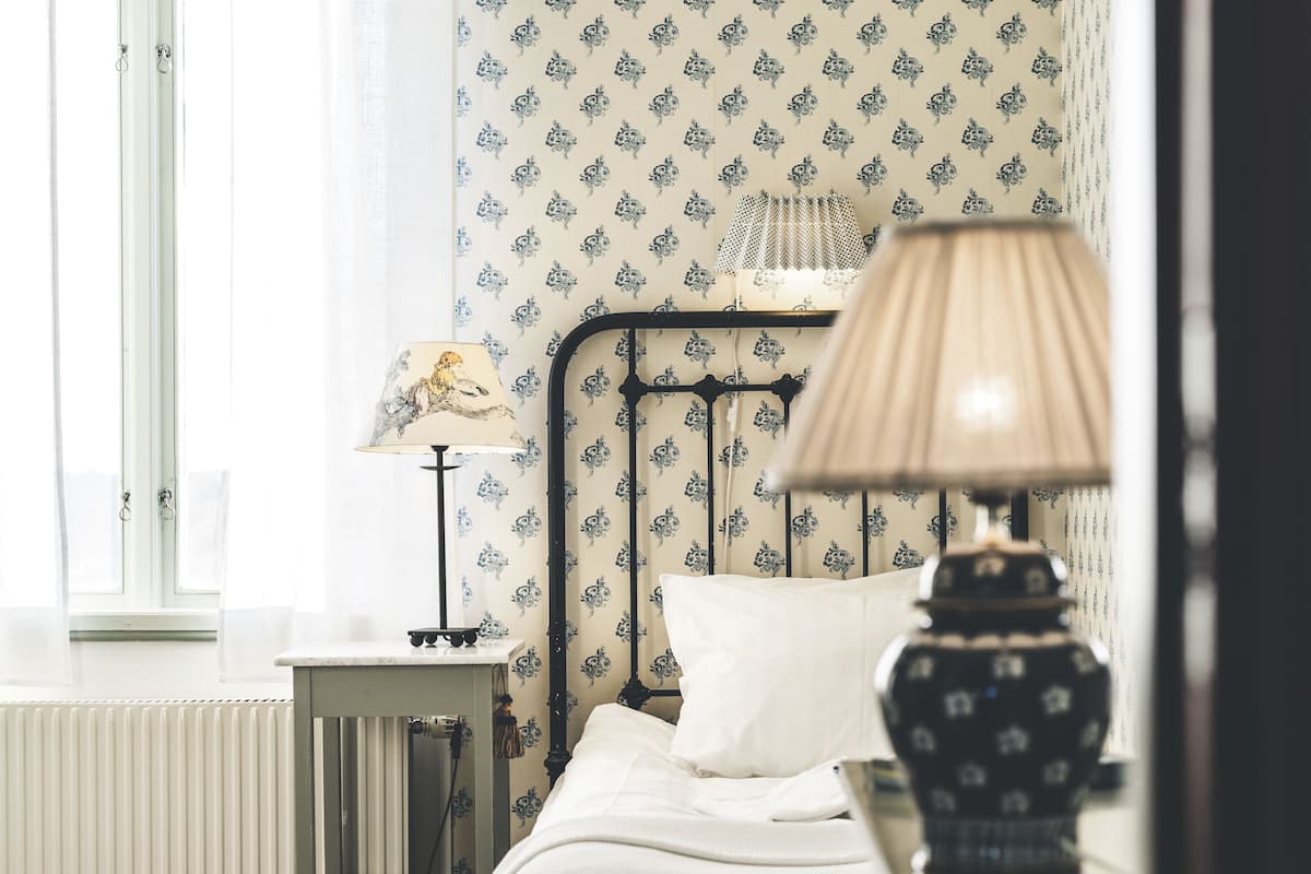 A bedroom with a bed, a nightstand, a lamp, and a radiator.