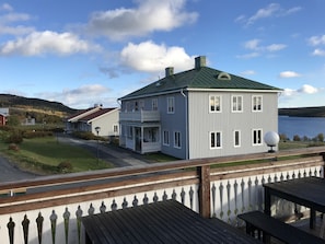 A two-story house with a balcony, a view of a lake, and a wooden deck. - Wångens wärdshus (Alsen)