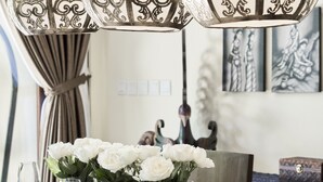 A dining table set with white flowers, wine glasses, and silverware, under ornate hanging lamps. - Kubu Gajah Villas (Denpasar)