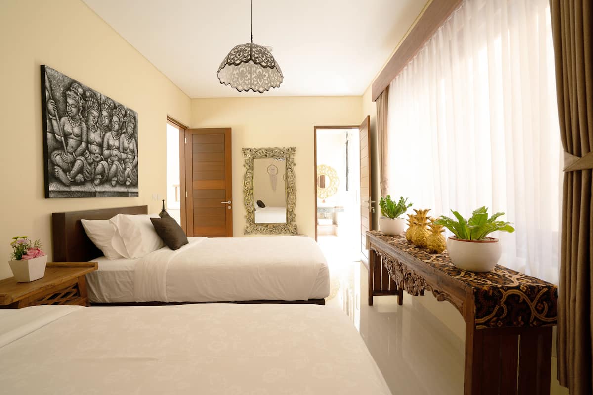A bedroom with a large bed, a wooden nightstand, a decorative mirror, and a potted plant on a console table.