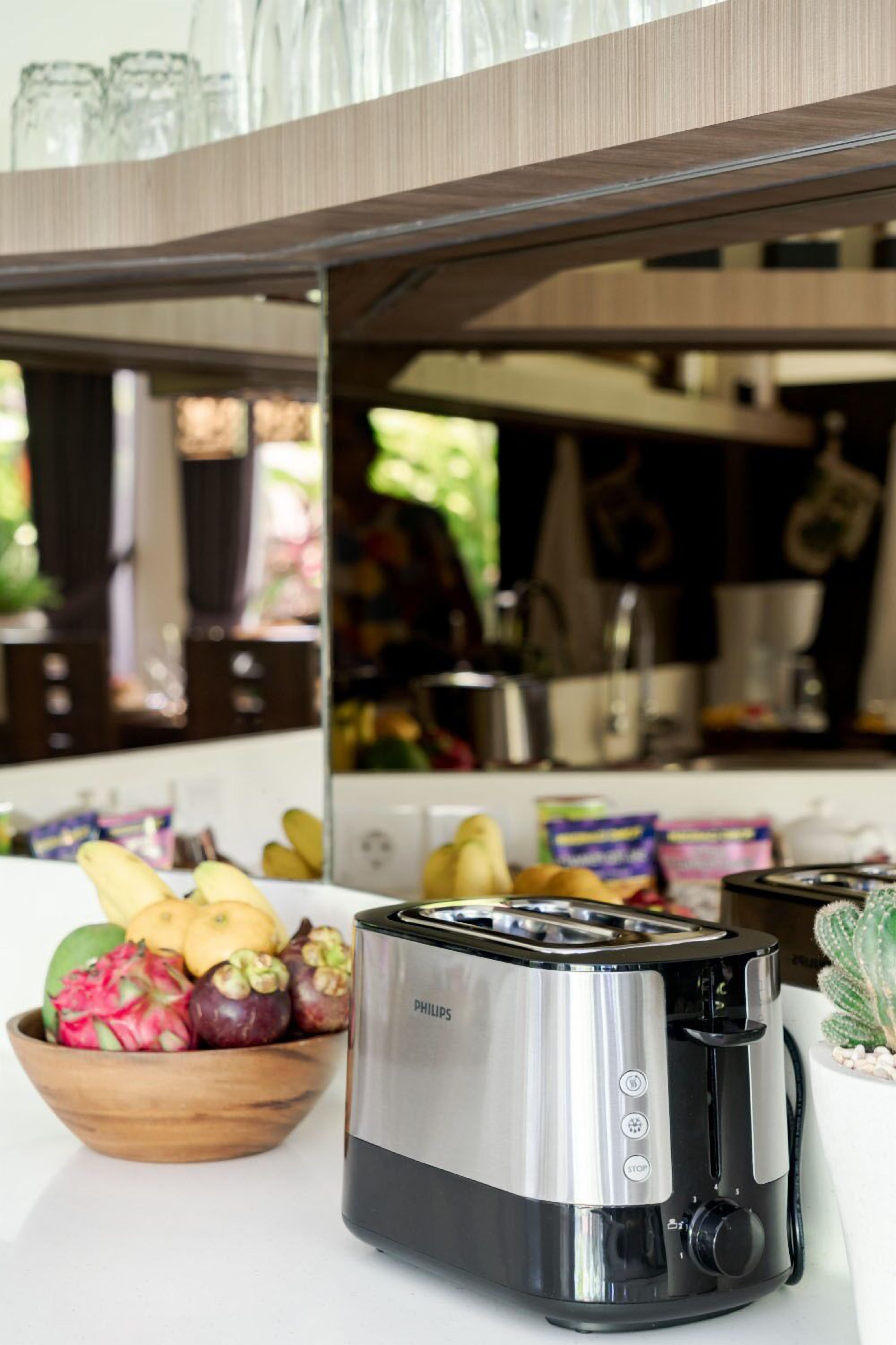 Une cuisine avec un grille-pain Philips, un saladier rempli de fruits et un cactus.