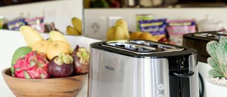 Une cuisine avec un grille-pain Philips, un saladier rempli de fruits et un cactus.