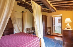 Ein Schlafzimmer mit Himmelbett, Holzmöbeln und Blick auf ein Badezimmer.