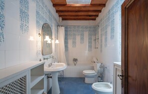 Ein Badezimmer mit Holzboden, einer Badewanne, einer Toilette und zwei Waschbecken.
