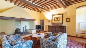 A cozy living room with a fireplace, patterned sofas, and a wooden ceiling. - Nice home in Barberino Val d'Elsa (Barberino Val d'Elsa)