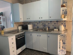 A compact kitchen with white cabinets, a microwave, a toaster, and a sink. - Relax and sun (Santa Pola)
