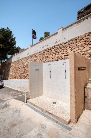 A stone wall with a tiled shower enclosure and a flag. - Relax and sun (Santa Pola)