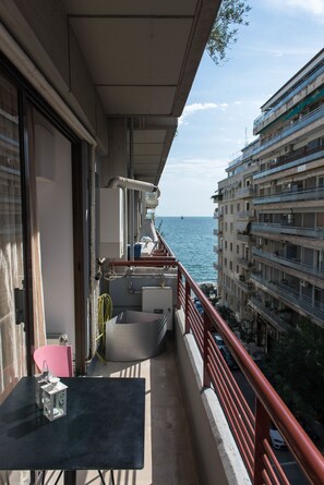 A balcony with a table and chairs, overlooking a body of water and adjacent buildings. - Fabulous Sea View Apartment (Thessaloniki)