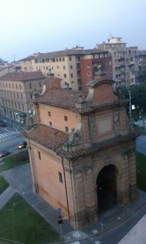 A historical building with a central archway, surrounded by a paved area and a street.