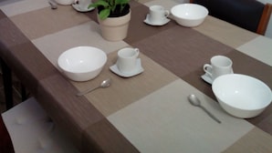 A dining table set with white dishes, a potted plant, and a spoon. - Il Cantuccio B&B (Bologna)
