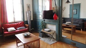 Een gezellige woonkamer met een rode bank, een houten salontafel en een televisie aan een blauwe muur.