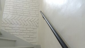Een trap met een witte bakstenen muur en een zwarte leuning.