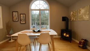 A dining area with a large arched window, a fireplace, and two chairs.