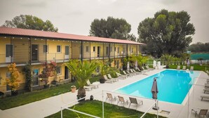 A yellow building with a swimming pool, lounge chairs, and potted plants. - Agriturismo Dolceluna (Milan)