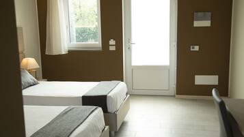 Une chambre avec deux lits, une fenêtre et une porte.