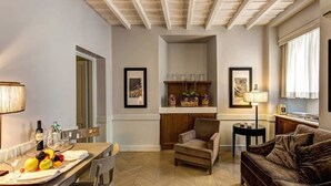 A cozy living room with a dining area, a sofa, and a small table with fruits and glasses. - Suite Giulia 1 (Rome)