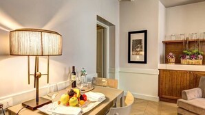 A dining area with a table set for two, a lamp, and a fruit platter. - Suite Giulia 1 (Rome)