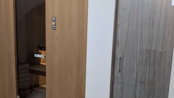 A room with a wooden wardrobe, a closed grey door, and a tiled floor.