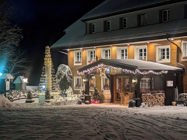 A hotel with a snow-covered entrance, a Christmas tree, and outdoor seating.