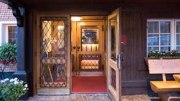 A wooden entrance with a red carpet, a metal gate, and a bench outside.