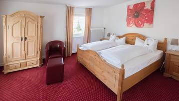 Un dormitorio con una cama de madera, un armario de madera, un sillón rojo y una alfombra roja.