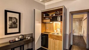 A compact kitchenette with a microwave, sink, and wooden cabinets. - Suite Giulia 2 (Rome)