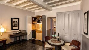 A compact hotel room with a kitchenette, a dining area with a round table, and a seating area with a chair. - Suite Giulia 2 (Rome)