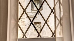 A view through a window with a metal grille, revealing a building facade with a sign that reads "VIA GIULIA". - Suite Giulia 2 (Rome)