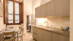 Una cocina compacta con una mesa y sillas de madera, un lavamanos empotrado y armarios.