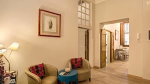Una sala de estar con dos sillones, una mesita redonda y un cuadro enmarcado en la pared.