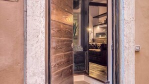 A wooden door leading into a room with a dark-colored sofa and a small table. - Trinità dei monti superior suite (Rome)