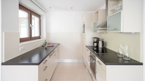 Una cocina moderna con encimera negra, electrodomésticos de acero inoxidable y una ventana con persianas.