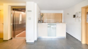 Un moderno vestíbulo de hotel con una isla central, una recepción y una puerta de madera.