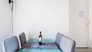 Una mesa de comedor con dos sillas, una botella de vino y una copa sobre un tapete.
