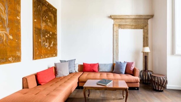 Una sala de estar con un sofá seccional, una mesa de centro, una lámpara y un espejo decorativo.