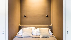 Un dormitorio con una cama, dos almohadas y dos lámparas colgantes.