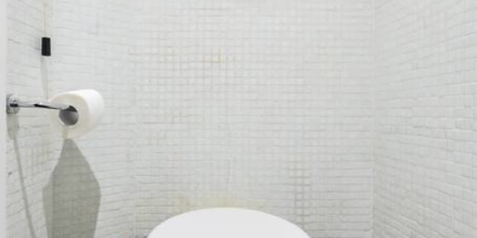 A bathroom with white tiled walls and a white toilet.
