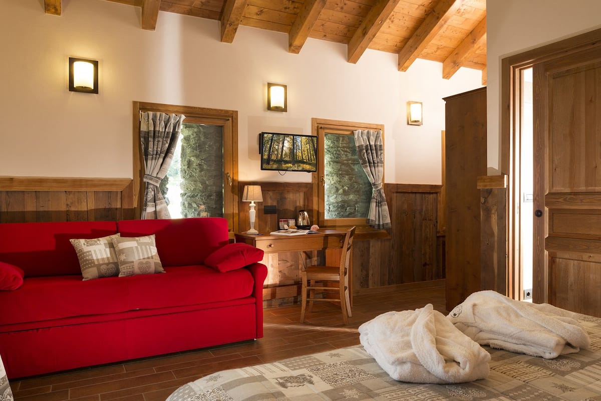Una habitación acogedora con un sofá rojo, paredes de madera y una chimenea de piedra.